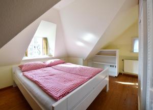 a bedroom with a bed with a red and white blanket at Im Apfelgarten in Oldsum