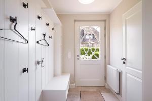 a hallway with a white door and a window at Reethaus Friesenjung in Hedehusum