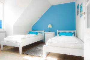 two beds in a room with a blue wall at Amoy - Werftstraße 2 in Heiligenhafen