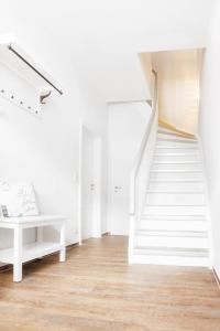 a white staircase in a white room with a bench at Amoy - Werftstraße 2 in Heiligenhafen