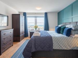 een slaapkamer met een bed, een ladekast en een raam bij Shorefront Apartment in Anstruther