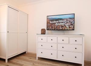 a bedroom with a white dresser with a tv on it at Meer-Liebe in Hörnum