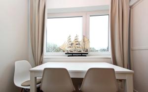 a white table with chairs and a boat in a window at Meer-Liebe in Hörnum +6 photos