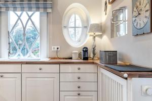 a kitchen with white cabinets and a clock on the wall at Hüs Lillebo in Hedehusum