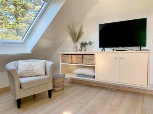 a living room with a tv and a chair at Sinfonie, Whg 5 in Tinnum