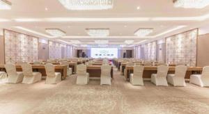 une salle de conférence avec des tables, des chaises et un écran dans l'établissement Shaoxing Yintai Hotel, à Shaoxing