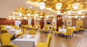 une salle à manger avec des tables blanches et des chaises jaunes dans l'établissement Shaoxing Yintai Hotel, à Shaoxing