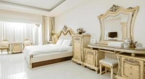 een witte slaapkamer met een bed en een spiegel bij Crystal Place Buayai in Bua Yai