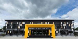 een zwart en geel gebouw met een gele deur bij Seven bee boutique hotel in Surin