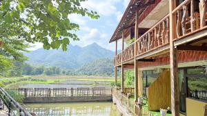 een gebouw met uitzicht op een rivier en de bergen bij La Mai Chau Home in Mai Chau