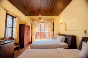 een hotelkamer met twee bedden en een raam bij Bualuang Hotel in Luang Prabang +8 foto's