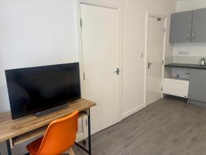 een kamer met een bureau, een televisie en een stoel bij Serene Studio in Dudley in Dudley