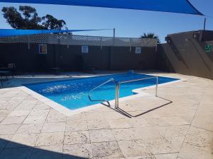 a swimming pool with a metal hand rail in it at Mandurah Foreshore Motel in Mandurah