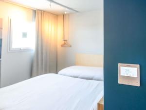 a bedroom with two beds and a clock on the wall at Ibis Budget La Rochelle Puilboreau in Puilboreau