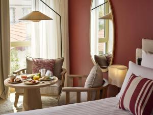 een hotelkamer met een bed, een tafel en stoelen bij Le Talaia Hôtel & Spa Biarritz - MGallery Collection in Biarritz