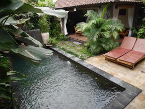 a backyard with a pond with a couch and chairs at Pondok Penestanan Villa Ubud in Ubud