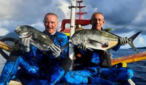 two men on a boat with fish in their hands at SIRUS Resort Tagulandang in Kisihang