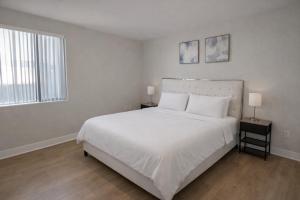 ein weißes Schlafzimmer mit einem großen Bett und zwei Fenstern in der Unterkunft Luxury 2 Bedrooms 2 Bathrooms With Pool and Gym in Los Angeles + 10 Fotos