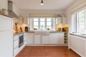una cucina con mobili bianchi e pavimento piastrellato di Haus Traumstraße a Hedehusum