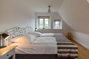 una camera da letto con un letto grande con lenzuola e cuscini bianchi di Haus Traumstraße a Hedehusum