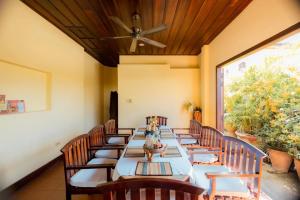 een lange tafel met stoelen en een plafondventilator bij Bualuang Hotel in Luang Prabang