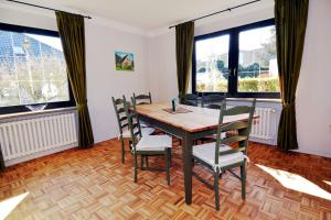 a dining room with a table and chairs and windows at Breslauer Haus in Heiligenhafen