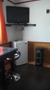 Habitación con nevera pequeña y TV en la pared. en Cabañas El Mirador, en Hornopirén
