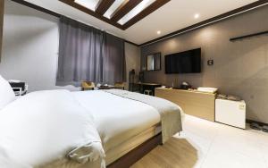 una camera da letto con un grande letto bianco e una televisione di 천안 호텔 하루 a Tujŏng-dong