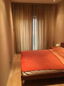 a bedroom with a bed with an orange comforter and a window at Zaga Solemar Apartment in Herceg-Novi