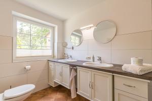 a bathroom with two sinks and a toilet and a window at Ferienwohnung Ina Meta in Reppenhagen