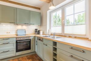 a kitchen with green cabinets and a sink and windows at Ferienwohnung Ina Meta in Reppenhagen