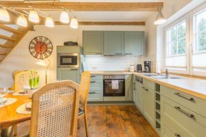 a kitchen with green cabinets and a wooden table at Ferienwohnung Ina Meta in Reppenhagen