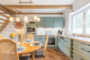 a kitchen with green cabinets and a wooden table at Ferienwohnung Ina Meta in Reppenhagen +21 photos
