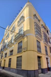 ein gelbes Gebäude mit verriegelten Fenstern auf einer Straße in der Unterkunft Reservaloen Casa del Museo in Sevilla