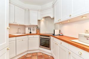 a kitchen with white cabinets and a wooden counter top at Inselhüs Kampen in Kampen