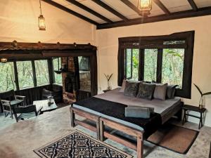 a bedroom with a bed in a room with windows at The Trogon Knuckles in Rangala