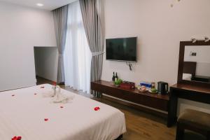 a hotel room with a bed and a flat screen tv at MAYA HOMESTAY villa in Hue +6 photos