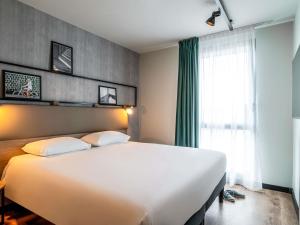een slaapkamer met een groot wit bed en een raam bij ibis Bordeaux Nord Carbon Blanc in Carbon-Blanc