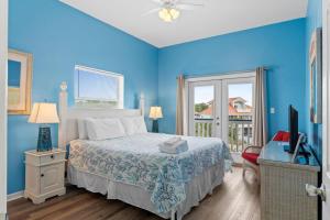 een blauwe slaapkamer met een bed en een televisie bij Dream Chaser-Private Pool-Pet Friendly-Directly across from boardwalk to beach in St. George Island +55 foto's