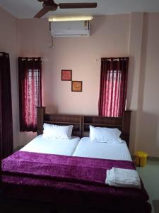 a bedroom with two beds with purple sheets and windows at Sakalam homestay in Trivandrum