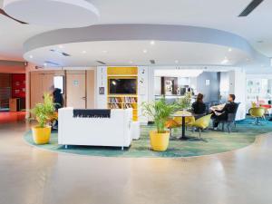 um grupo de pessoas sentadas em mesas em um lobby em ibis Styles Lyon Sud Vienne em Chasse-sur-Rhône