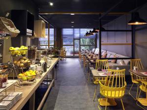 a restaurant with yellow chairs and tables and a couch at Mercure Paris Sud Les Ulis-Courtaboeuf in Les Ulis