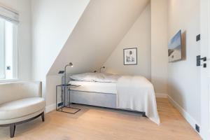 a white bedroom with a bed and a chair at Hüs Amy in Rantum