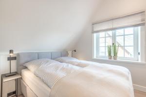 a white bedroom with a bed and a window at Hüs Amy in Rantum +28 photos