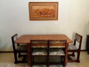 un tavolo in legno con due sedie e una foto sul muro di Panache Wildlife Cottage-Self Catering a Hoedspruit