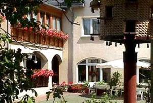 a building with flowers and a patio with tables and chairs at Landhotel Sperlingsberg in Crimmitschau +25 photos