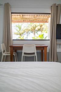 a bedroom with a bed and a window with a table and chairs at The Rock Coco Villa in Ban Laem Pom
