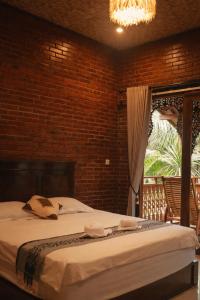 een slaapkamer met een groot bed met een bakstenen muur bij Java Turtle Lodge Meru Betiri in Banyuwangi
