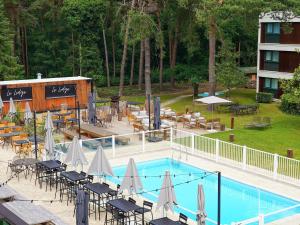 una piscina con sedie e ombrelloni accanto a un hotel di Novotel Rouen Sud Zenith Parc Expo a Saint-Étienne-du-Rouvray