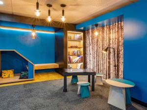 een bibliotheek met blauwe muren en een tafel en twee krukken bij Novotel Le Mans in Le Mans